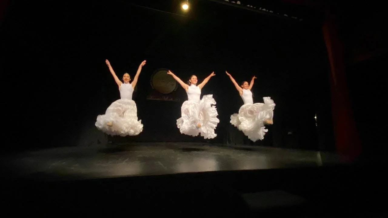 Tres bailarinas del estudio en un salto durante una presentación en escenario