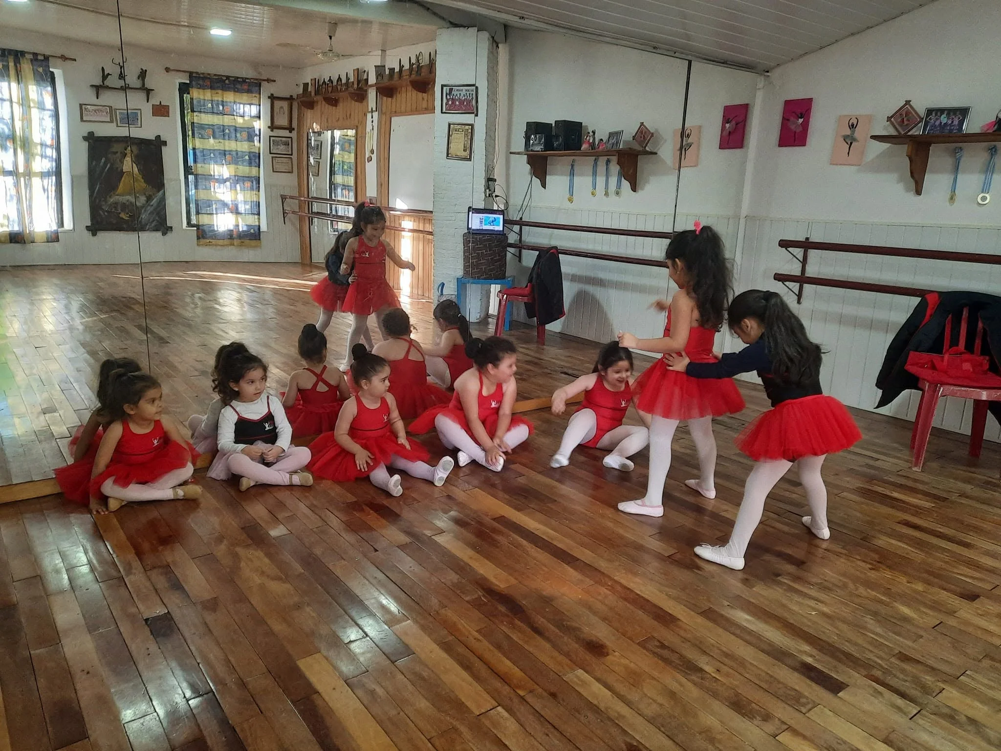 Alumnas pequeñas reunidas en el salón de danza, con espejos, barras y piso de madera